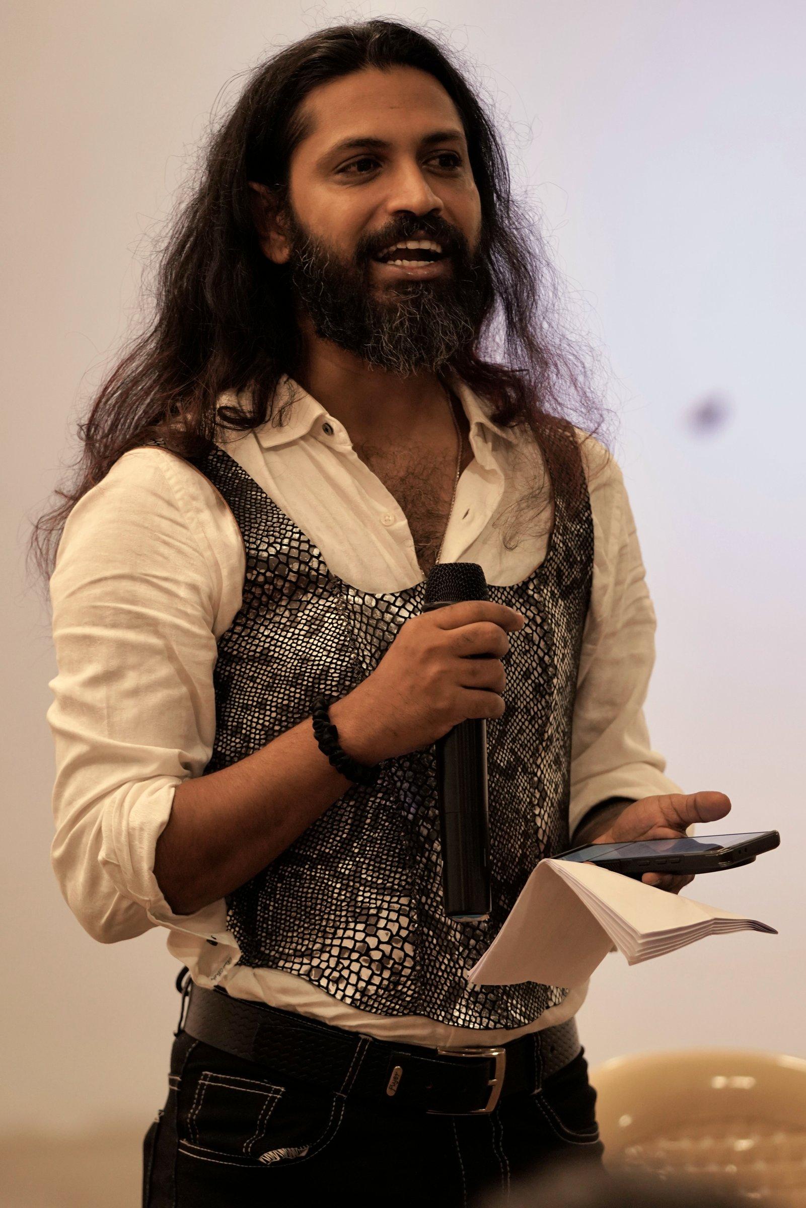 Shyam speaking at an event, wearing the first Kavach